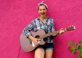 Girl with guitar on pink wall