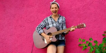 Girl with guitar on pink wall