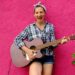 Girl with guitar on pink wall